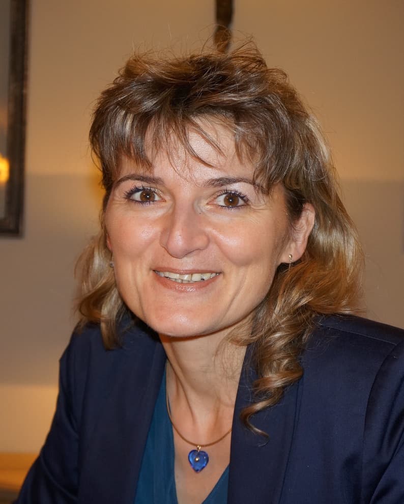 Portrait de Domitille Raillon, écrivain public, souriante en blazer bleu marine